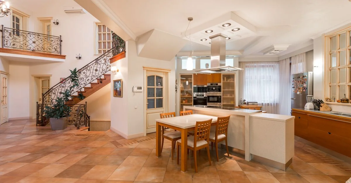 Cuisine moderne élégante et spacieuse avec un espace repas luxueux et un bel escalier, offrant une atmosphère chaleureuse.