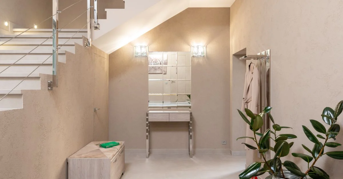 Un hall d'entrée contemporain beige avec un escalier moderne, des plantes et une décoration élégante.