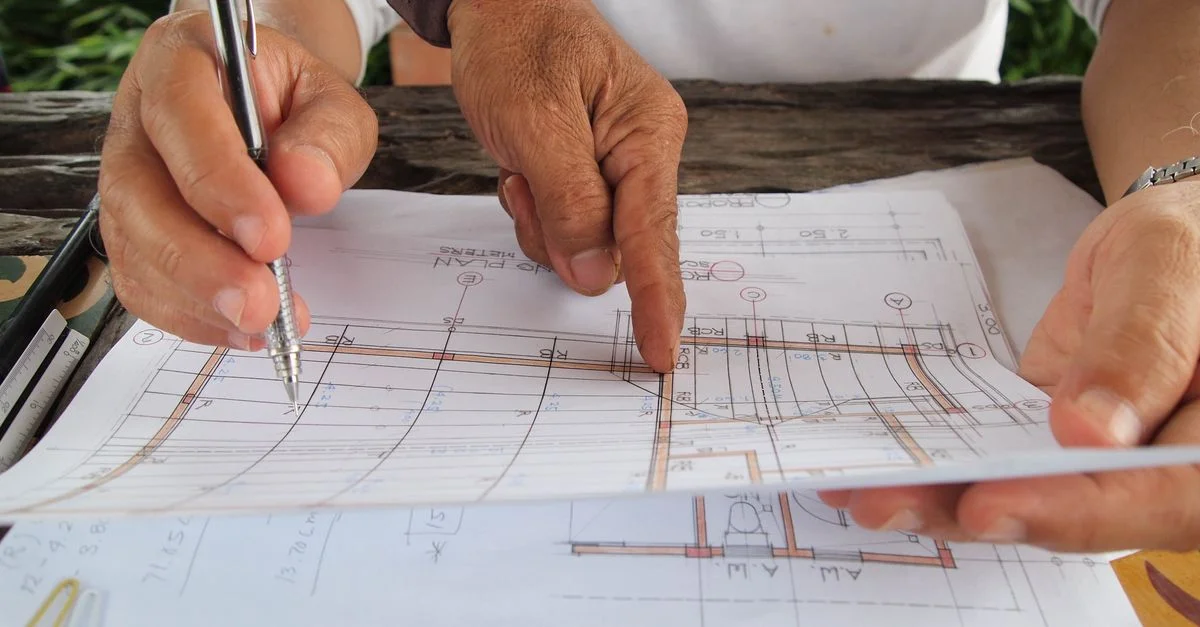 Deux architectes examinent et discutent des plans détaillés dans un espace de travail.