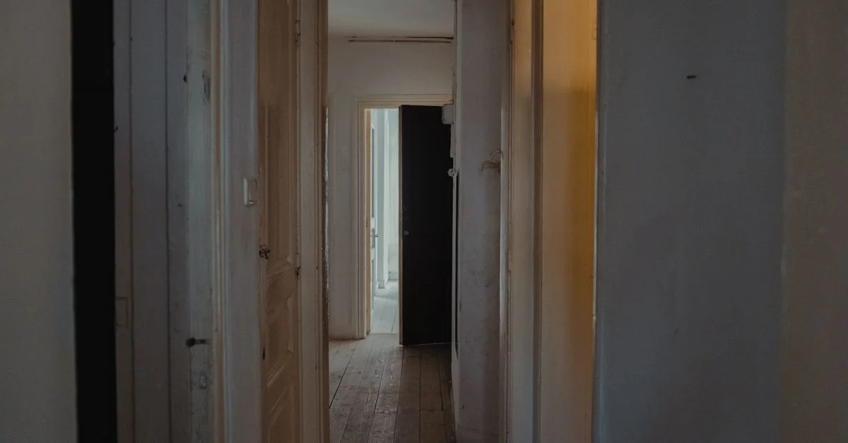 Un couloir faiblement éclairé dans un appartement avec des portes en bois et une ambiance rustique.
